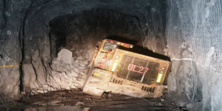 The back view of a loader in an underground stope. The right side has sunken into the floor.